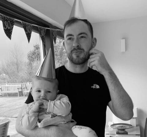 a person wearing a party hat holding a baby